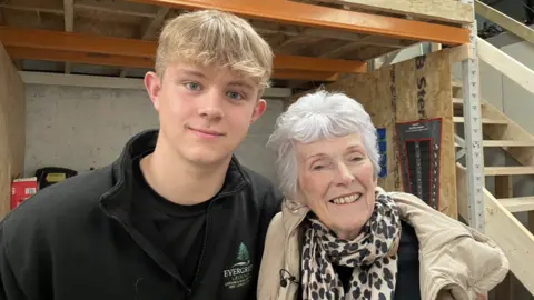 Jack Roberts Jack Roberts is pictured standing with his arm around his grandmother, Wendy Richardson, who smiles into the camera. Wendy has short, styled white hair and is wearing a leopard-print scarf, black t-shirt and beige coat. 