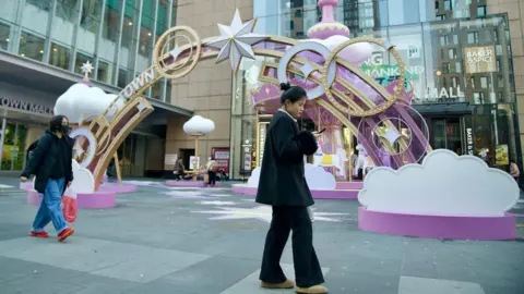 Two woman walk past a display outside a shopping mall in Beijing.