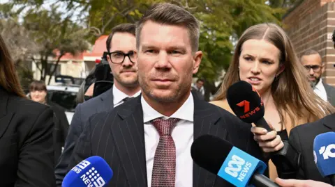 Australia's former cricketer David Warner (C) leaves Waverley Local Court in Sydney on August 18, 2026, after being fined and ordered to use a vehicle breathalyser lock following his admission to a drink-driving offence.