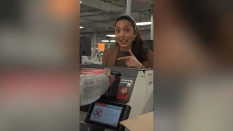 A woman with dark hair pulled away from her face points at exams being loaded into a machine