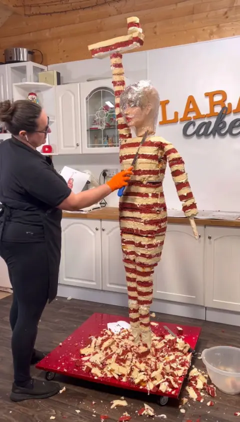 Lara Mason Lara Mason making the life-size cake, with the cake layers visible from the neck down