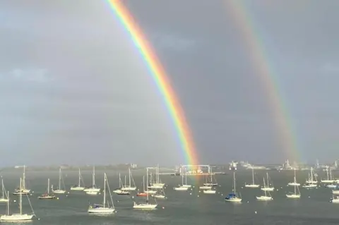 Caz A double rainbow over the sea, a flotilla of sailing boats beneath.