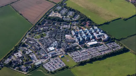David Goddard/Getty Images An aerial view of a large complex with big buildings surrounded by fields and grass.