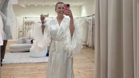 A woman in a wedding dress taking a selfie photograph