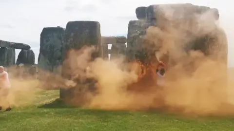 Just Stop Oil Stonehenge with a cloud of orange paint