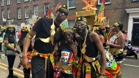 BBC/Julita Waleskiewicz Michael Sarkodie dressed in black with patterned belts and gold dressings