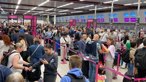 Passengers queue at Luton Airport