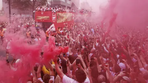 Arsenal players celebrate with the Premier League trophy on an open-top bus during Arsenal Champions Parade in north London on Sunday. 