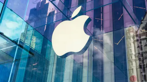 Getty Images The Apple logo on a window, with a city scene including skyscrapers reflected on the window
