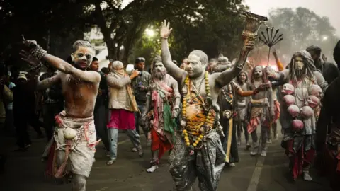 Orang-orang suci yang berlumuran abu menari dan memasuki festival 