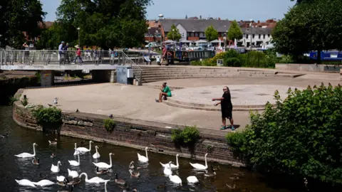Jacob King/PA Media A man feeds swans and ducks in Stratford-upon-Avon in Warwickshire. 