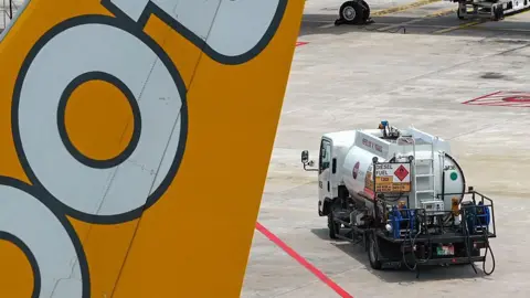 Getty Images A refuelling truck carrying aviation fuel is pictured next to a Scoot passenger jet at Singapore Changi Airport in Singapore 