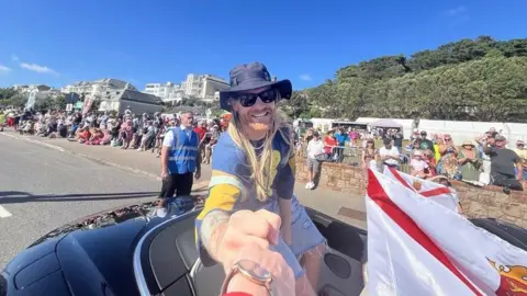 Sam Ryder on a car on Victoria Avenue gives the photographer a fist bump