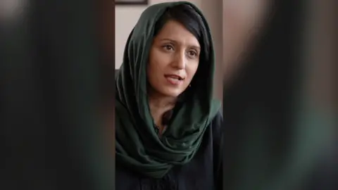 Yogita Limaye wears a dark green headscarf.