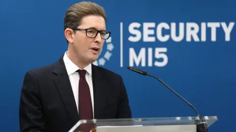 Jonathan Brady/PA Wire Ken McCallum, Director General of MI5 - a middle-aged man with slicked back dark brown hair, and wearing dark-rimmed rectangular glasses. He is wearing a dark suit, white shirt and navy blue tie.