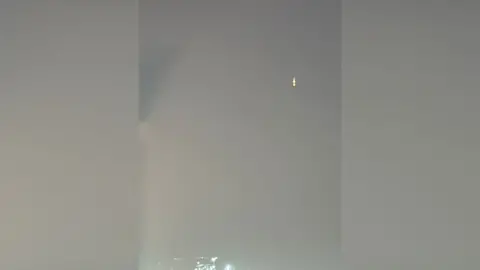 Hannah Carter A drone in the air over Dubai. It is a speck in the distance in a night sky.