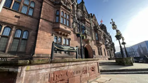 The headquarters of Coventry City Council, an ornate sandstone building with lead lined windows. The words The Council House are on the front.
