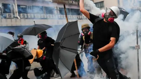 Reuters A protester throws tear gas canisters as they clash with riot police during protests in Hong Kong in 2019