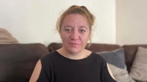 BBC Sarah Alves looking at the camera sat on a sofa