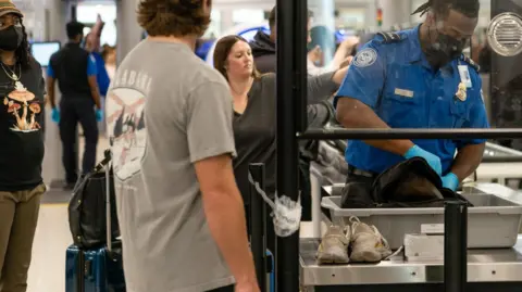 A Transportation Security Administration official checks the belongings of an airline passenger during a security screening