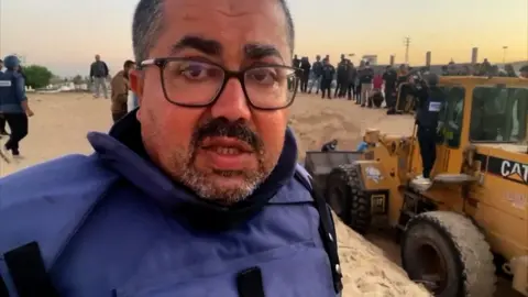 BBC Arabic reporter Adnan El-Bursh with digger behind him