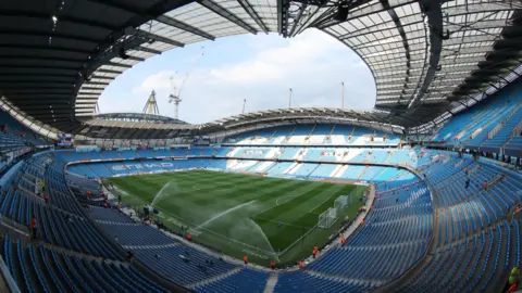 EPA Ultra wide angle photograph inside Etihad Stadium before a Premier League game. There are tens of thousands of light blue seats and a smattering of fans who have arrived very early.