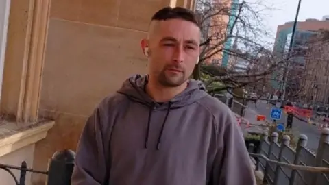 Robbie Robertson outside Dundee Sheriff Court. He is wearing a grey hooded top.