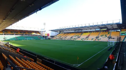 PA Media A large green football pitch with yellow seats surrounding it. 