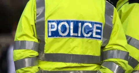 The back of a high-vis police jacket, with the word 'police' written in capital letters across the back.