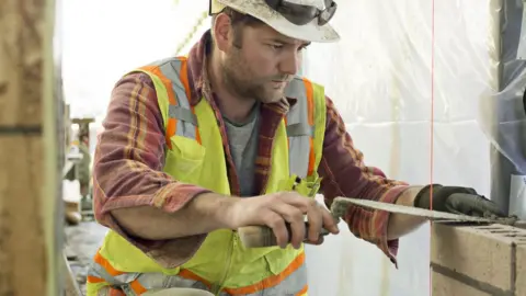Getty Images Man laying bricks on building site