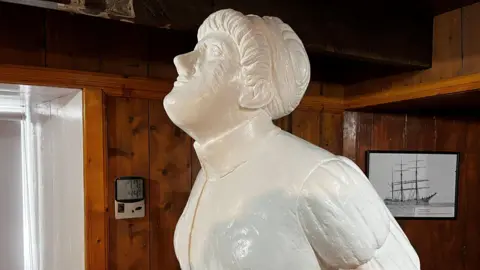 The figurehead portrays a woman with her hair tied up and her head looking up towards the sky.