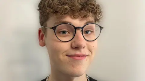 Thomas Fage Thomas Fage is a 19-year-old white man with blue eyes and curly dirty blonde hair. He wears round black-rimmed glasses and smiles at the camera. 