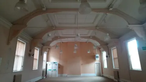 An empty hall with lighting and windows with the blinds drawn