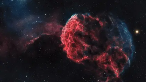 Nigel Stanbury / PA A blue and pink supernova in the night sky.