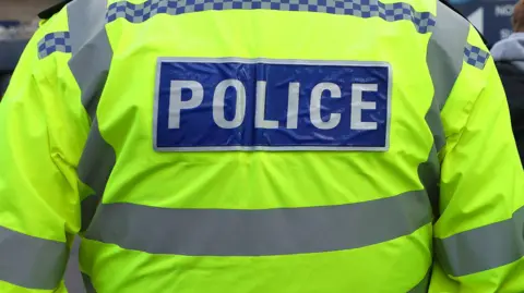 PA Media The back of a police jacket with a label reading police