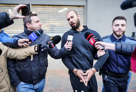 AFP Andrew Tate talks to media as he leaves Romania's anti-organized crime and terrorism directorate in Bucharest, Romania, on 25 January 2023