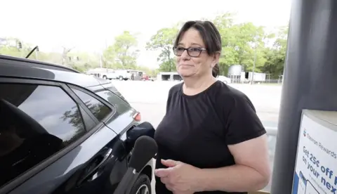James Cooke/BBC American driver Donna being interviewed as she fills her car with fuel