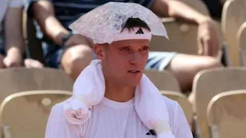 Jakub Mensik sits with an ice pack on his head during his first-round match at the French Open