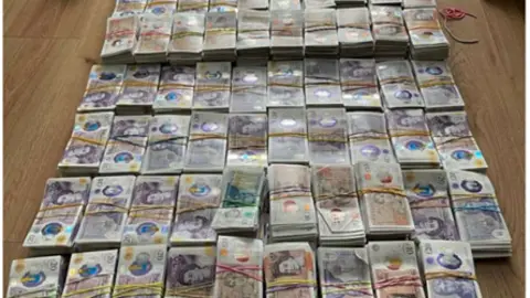 Wads of bank notes tied up in elastic bands on the floor of a property.