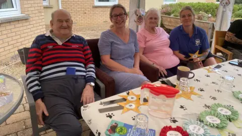 Natalie Crampton The judges sitting at a table in front of colourful rosettes for the winners