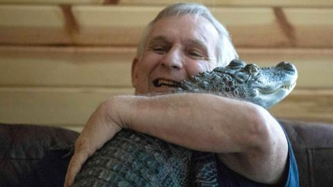 Joie Henney, 65, hugs his emotional support alligator named Wally 