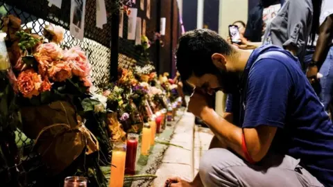 Leo Soto, 25, who lost his friend in the disaster, reacts as people hang up signs of missing residents