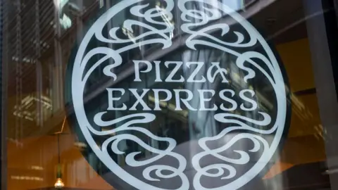 Getty Images A generic Pizza Express sign in a restaurant window. The sign has the name of the restaurant in a circle.