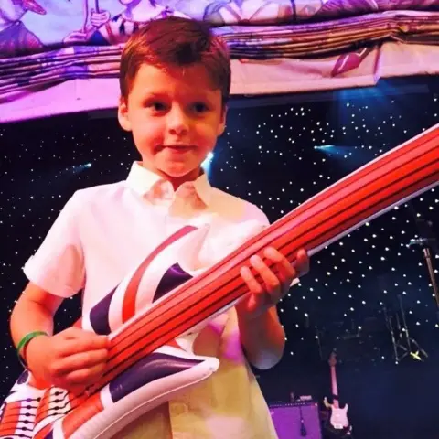 Family photo Fraser playing a blow-up guitar