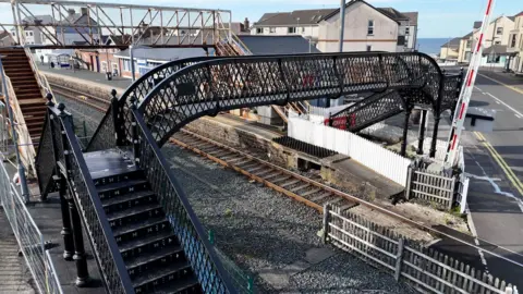 A black metal bridge over train tracks. 