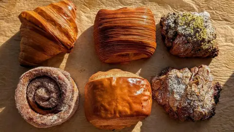 Astrid Roussel Six pastries are pictured in this photograph, including croissants, pain au chocolat and a cinnamon roll. They're displayed in two rows of three.