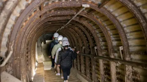 National Trust A number of visitors wearing safety helmets touring the Fan Bay Deep Shelter, which is a tunnel network built to house soldiers station at Fan Bay Battery in Dover, Kent.