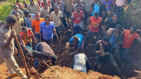 BBC/Habtamu Tibebu Mensen graven op de plek van twee aardverschuivingen in Zuid-Ethiopië - 24 juli 2024.