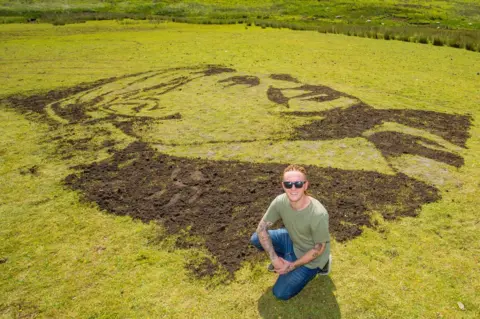 PA Artist Nathan Wyburn with his portrait of NHS founder Aneurin Bevan which has been unveiled on a Welsh mountainside to celebrate 70 years of the service