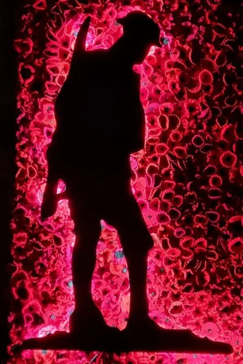 Christine Sinclair  A lit display of a World War One soldier framed with knitted poppies.
